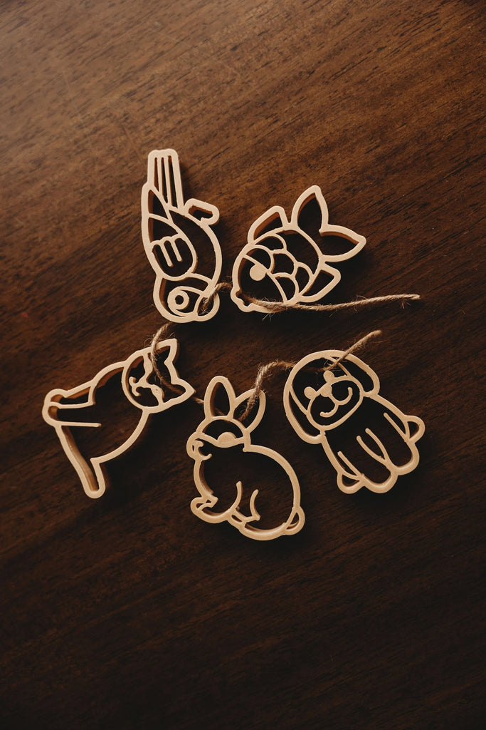 Top-down view of pet-themed dough cutter impressions on brown background, showing cat, dog, fish, rabbit, and bird in play-ready layout.