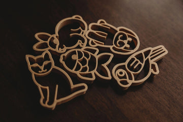 Flat lay of Kinfolk Pantry Pets Cutter Set on a wooden surface, featuring 5 biodegradable animal shapes: cat, dog, rabbit, fish, and bird.