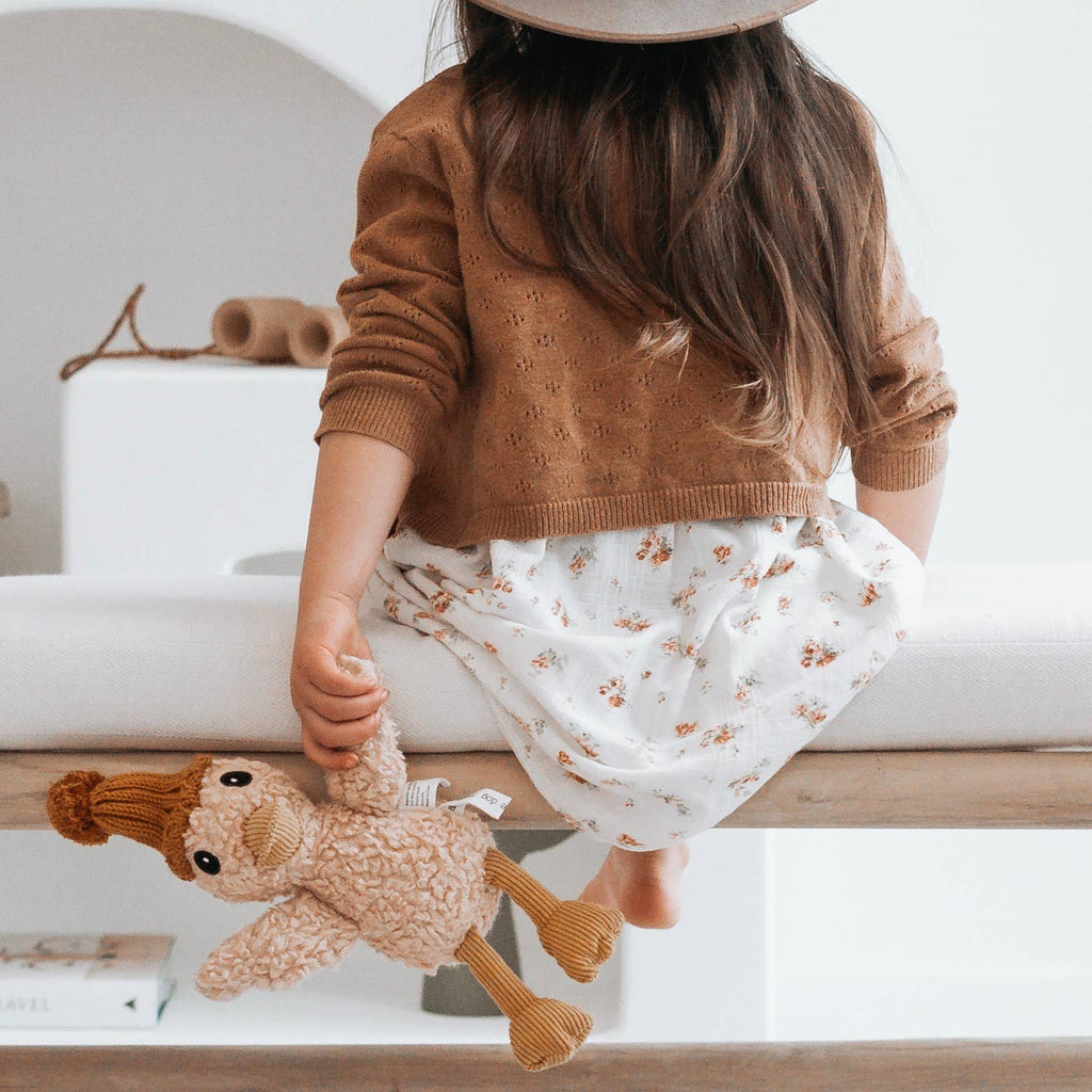 Child sitting on a bench holding Petunia Duck soft toy, showing playful design and soft tactile fabric.