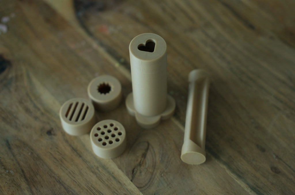 Kinfolk Pantry dough extruder set with pusher and shape lids, styled for playtime with earth-toned tools and natural materials.