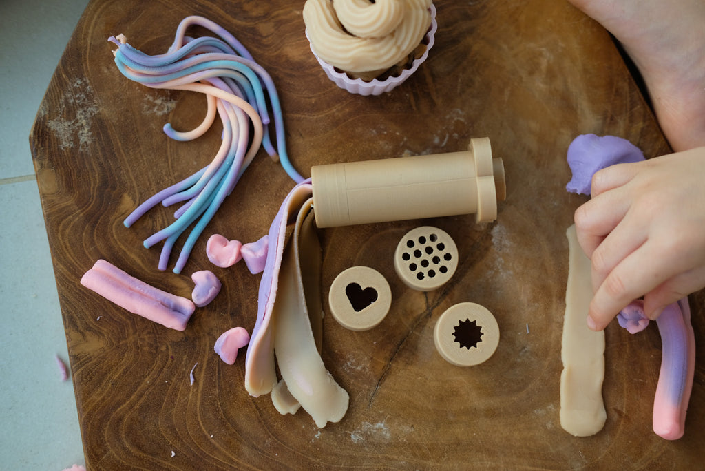 Child using eco dough extruder with colourful playdough on table, showing biodegradable components in action.