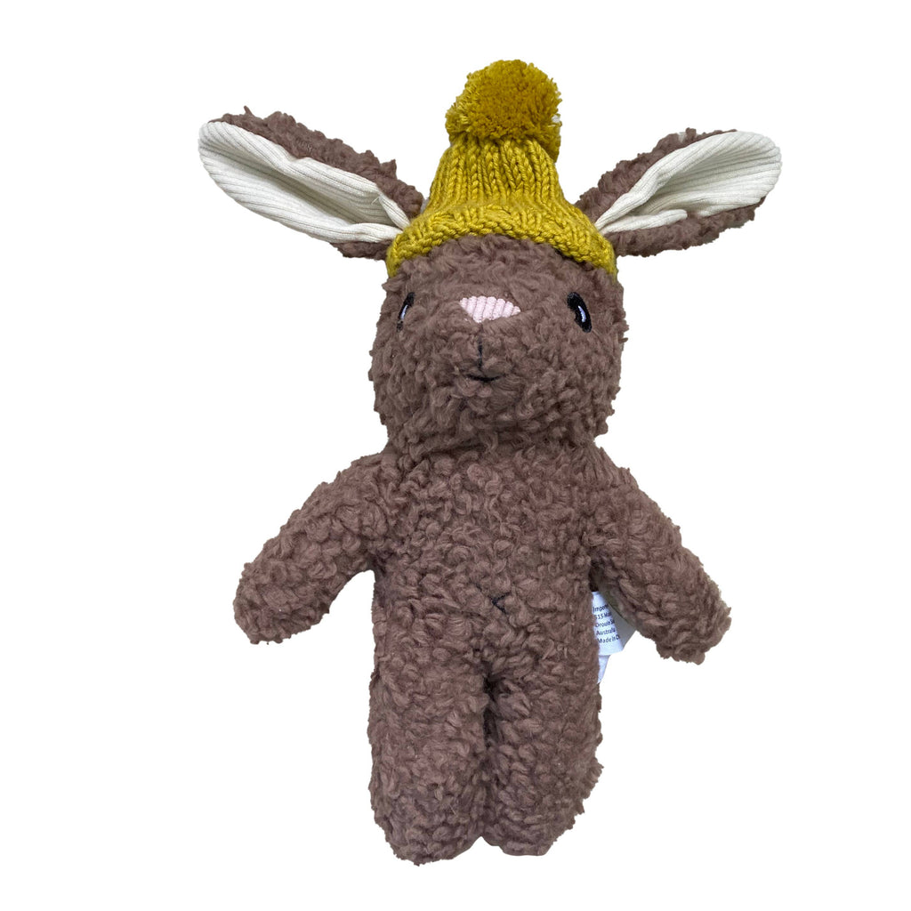 Stella Rabbit soft toy made from brown cotton plush fabric, featuring long floppy ears lined with cream fabric and wearing a mustard yellow knitted beanie with pom-pom.