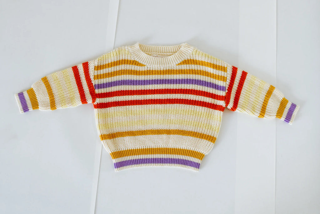 Flat lay of the Art Club Knit jumper – front view – showing colourful horizontal stripes in red, purple, and yellow on a cream cotton base.