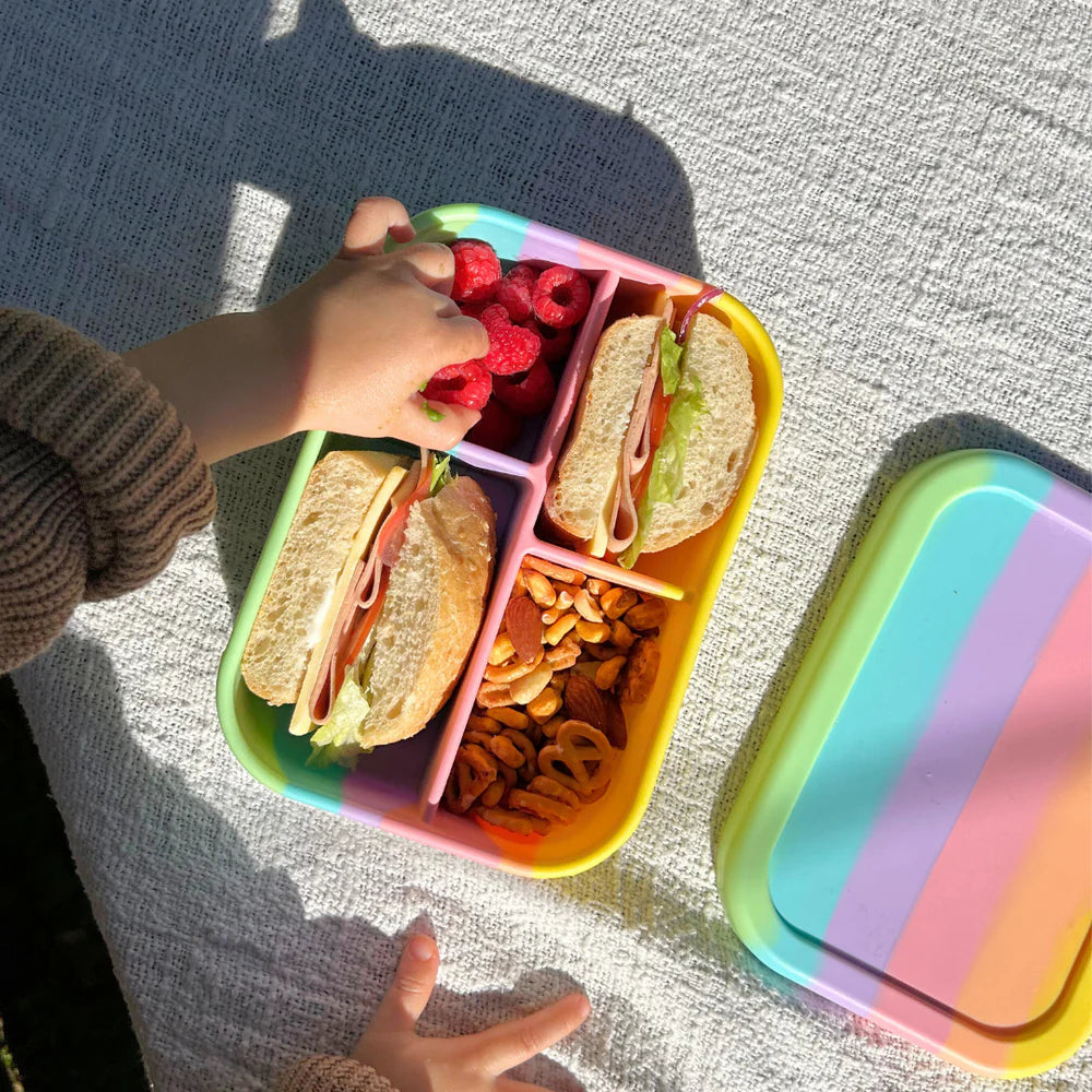 Child reaching for raspberries from Rainbow Midi Box—eco-friendly, reusable lunchbox perfect for school or outdoor adventures.