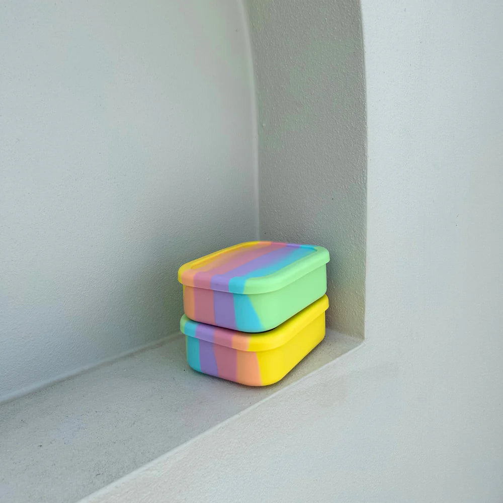 Stacked Rainbow Midi Boxes on a white ledge—vibrant and compact reusable lunch containers by The Zero Waste People.