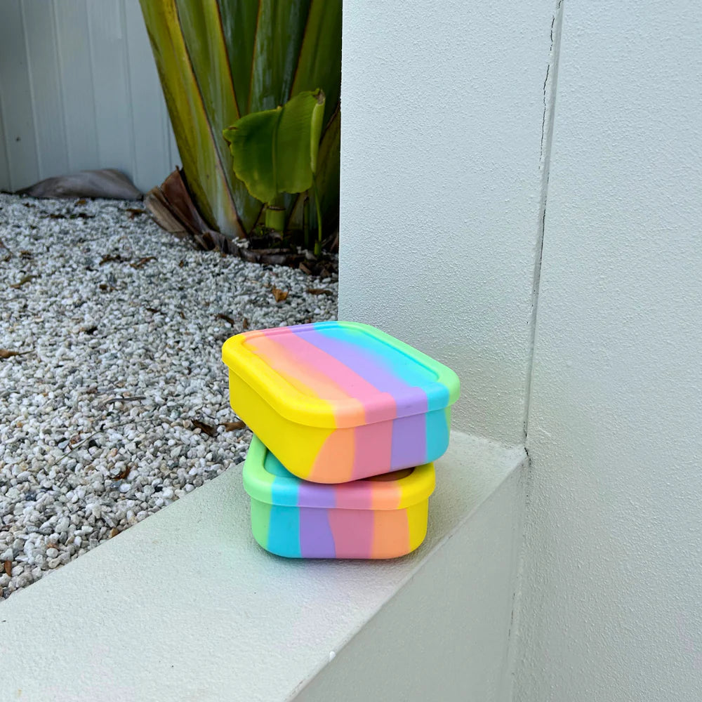 Two stacked Rainbow Mini Munchboxes on white ledge—durable, compact, and leak-proof lunch containers for kids and families.