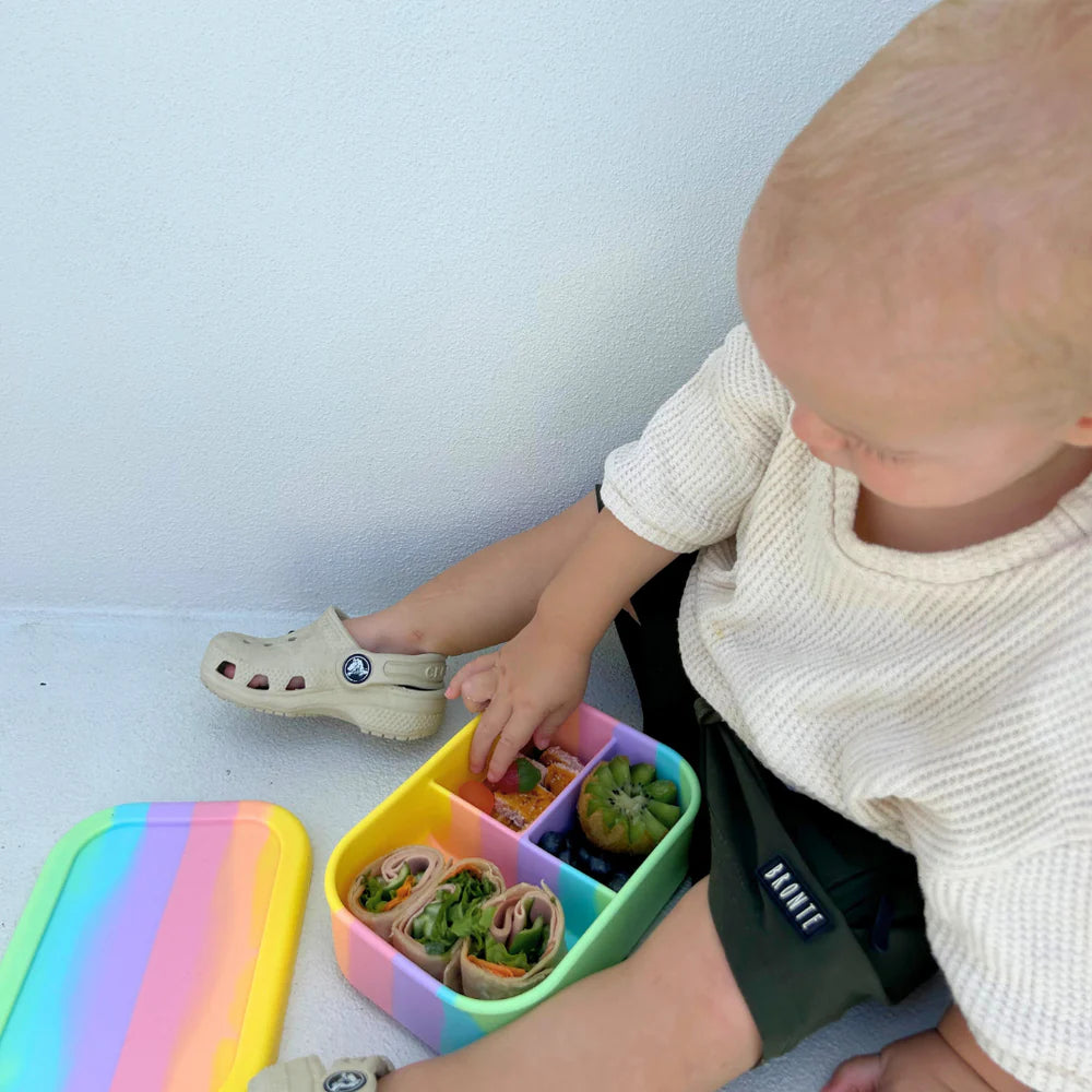 Toddler eating from a Rainbow Mini Munchbox—kid-friendly lunchbox designed for easy snacking at home or on the go.