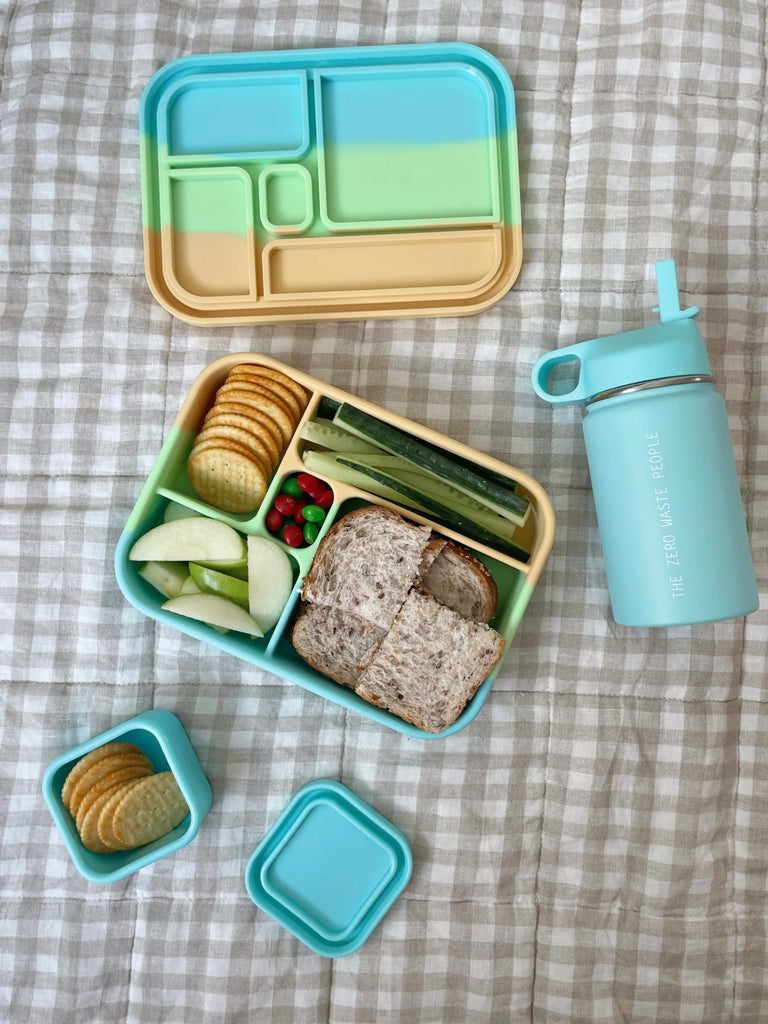 Open Bento Lunchbox in pastel colours filled with sandwich, crackers, fruit, and veggies – eco-friendly lunch solution for school or work.