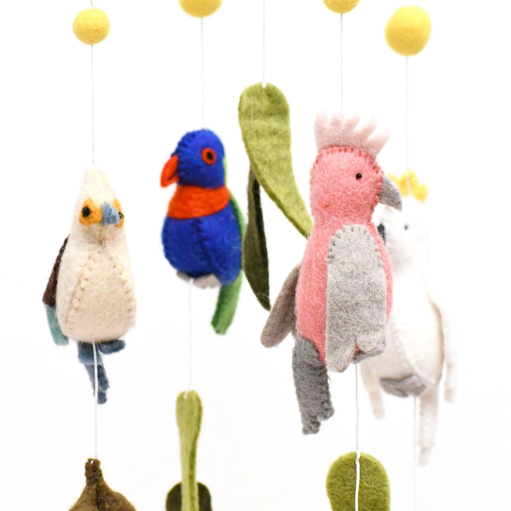 Handmade Australiana-themed nursery cot mobile featuring felt birds like a Cockatoo, Rainbow Lorikeet, Kookaburra, and Galah, surrounded by gum leaves, blossoms, and yellow wattle flower pompoms.