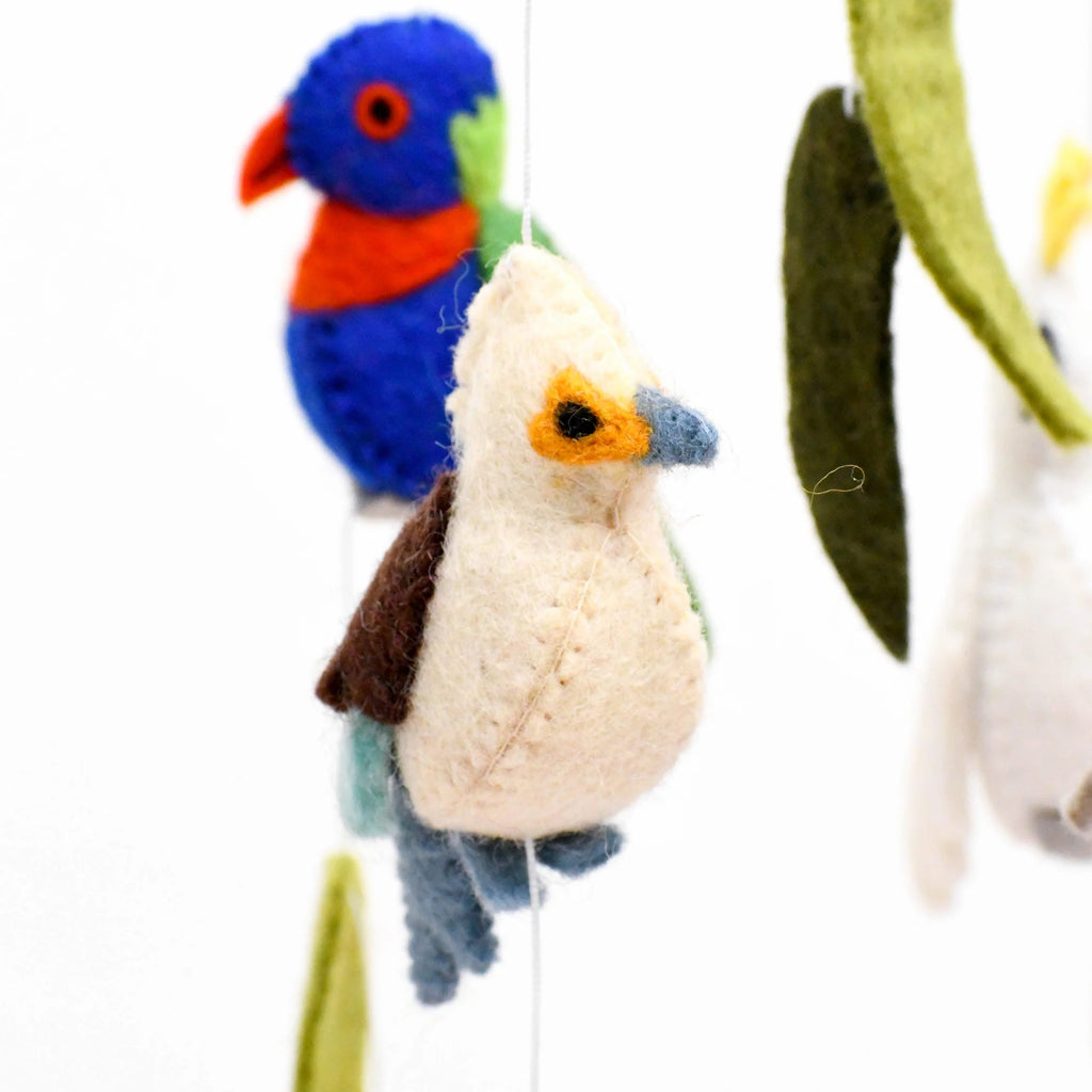 Handmade Australiana-themed nursery cot mobile featuring felt birds like a Cockatoo, Rainbow Lorikeet, Kookaburra, and Galah, surrounded by gum leaves, blossoms, and yellow wattle flower pompoms.