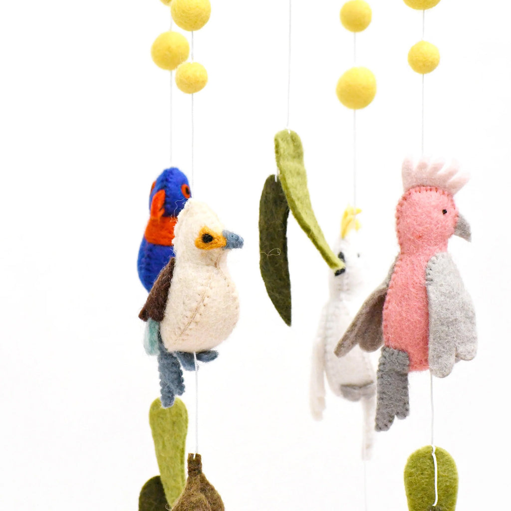 Handmade Australiana-themed nursery cot mobile featuring felt birds like a Cockatoo, Rainbow Lorikeet, Kookaburra, and Galah, surrounded by gum leaves, blossoms, and yellow wattle flower pompoms.