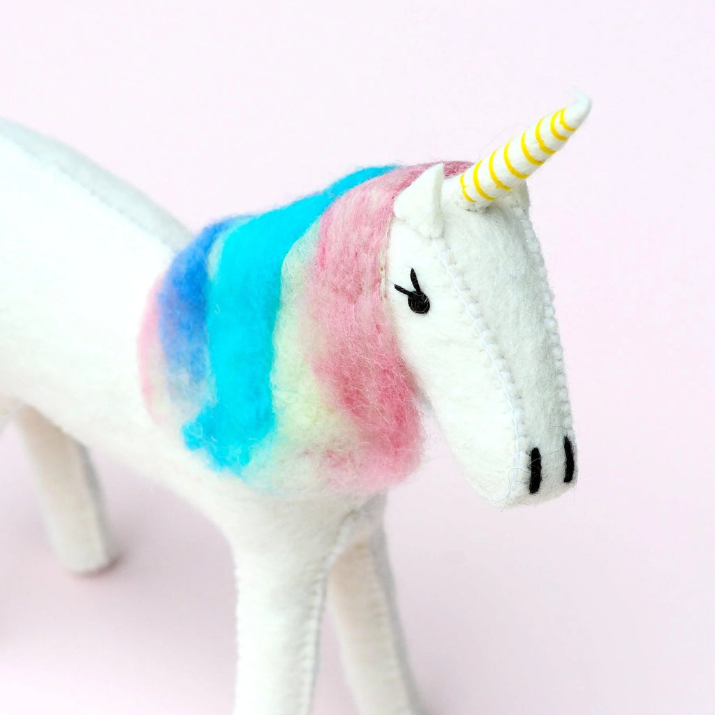 Close-up of unicorn’s face showing embroidered eyes and soft rainbow felt mane.