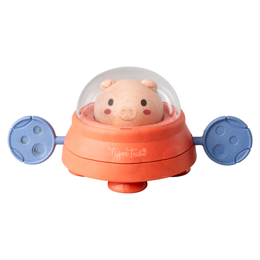 Close-up of the Space Piggy bath toy with a clear dome helmet and pink face, blue paddles, and bright orange body, ready for water play.