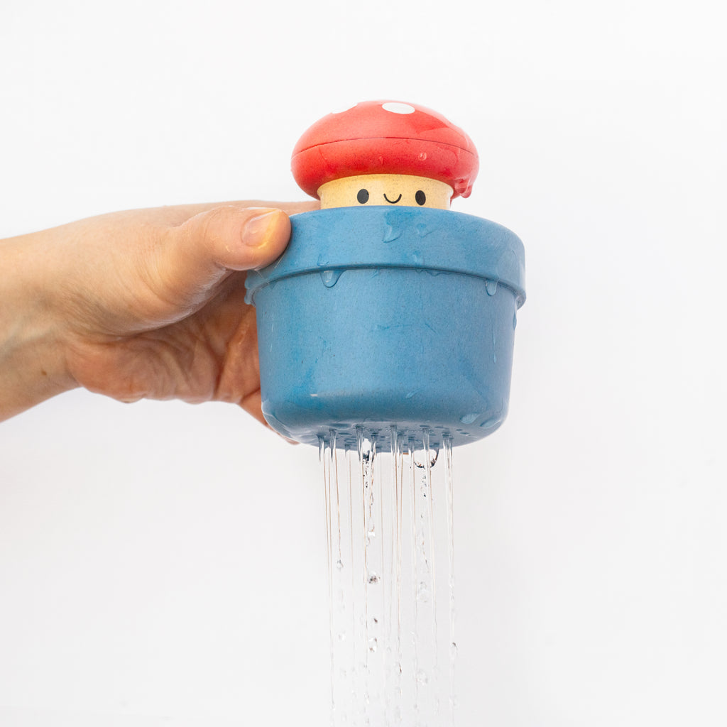 Adult holding the Mushroom bath toy as water drains from its holes, demonstrating the fun cause-and-effect water-sprinkling feature.