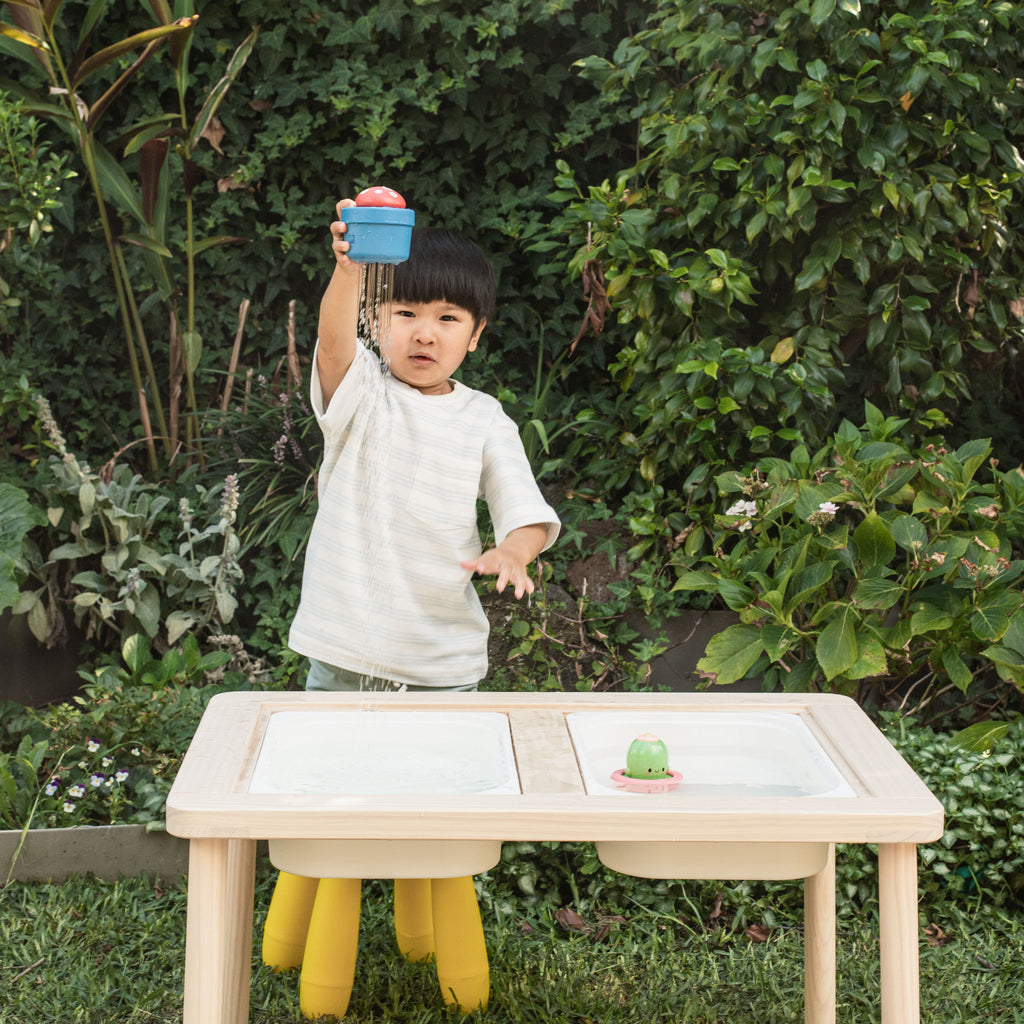 Child lifting the Bath Pop-Up Mushroom over their head, showing water trickling down and engaging in active bath-style fun outdoors.