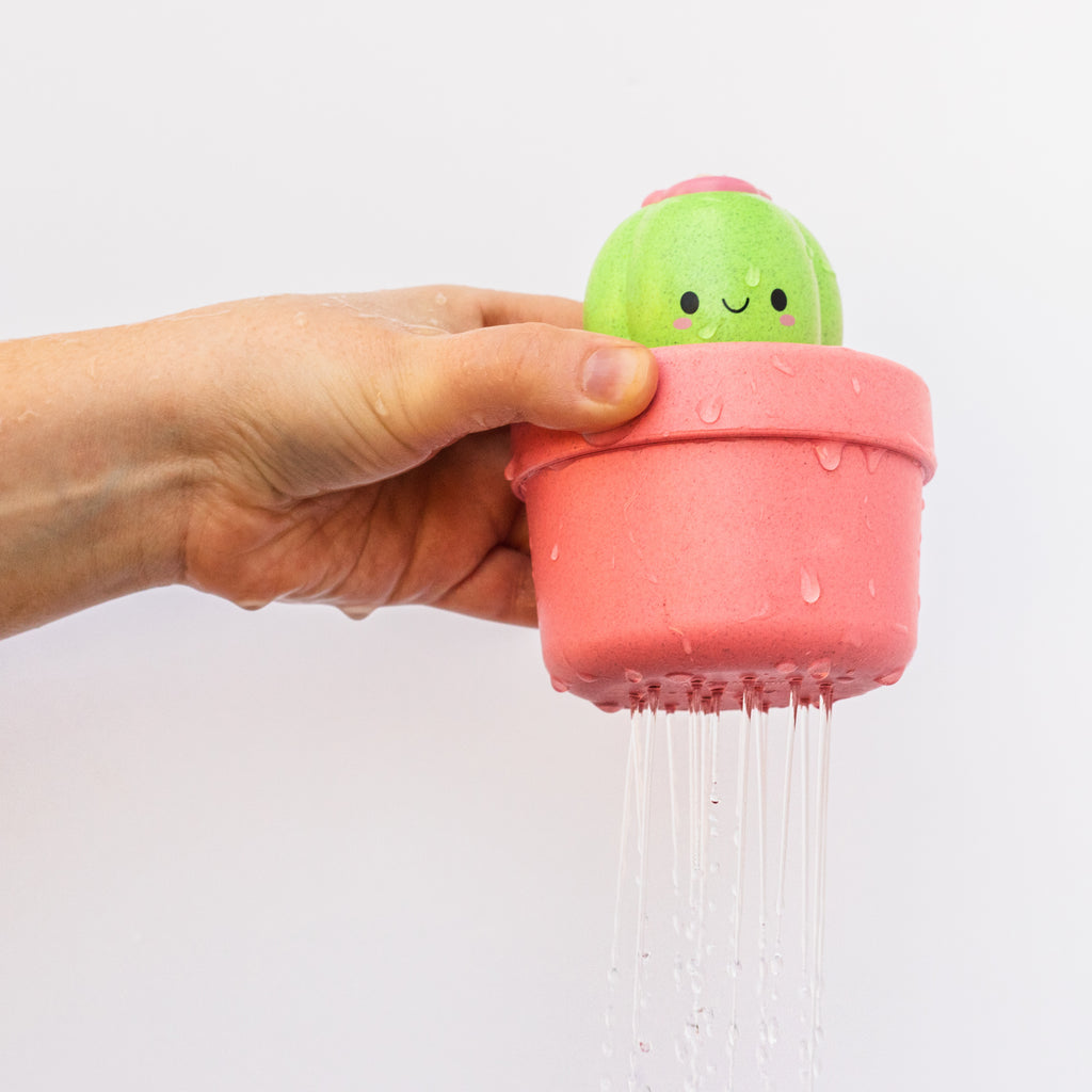 Adult hand holding the cactus bath toy as water drains through the holes in the bottom, demonstrating cause-and-effect learning in action.