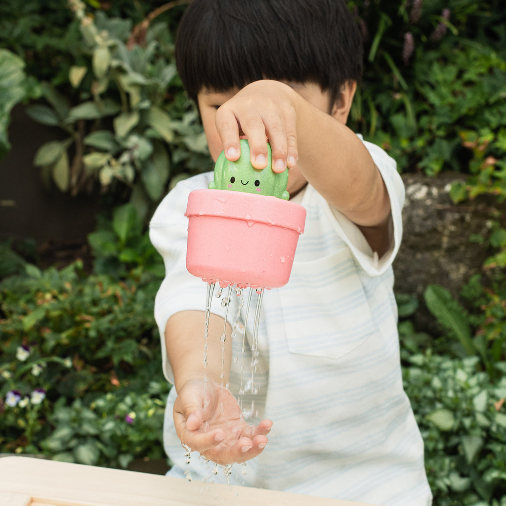 Child holding the cactus toy in a garden setting, showing real-life play and interaction with the pop-up function.
