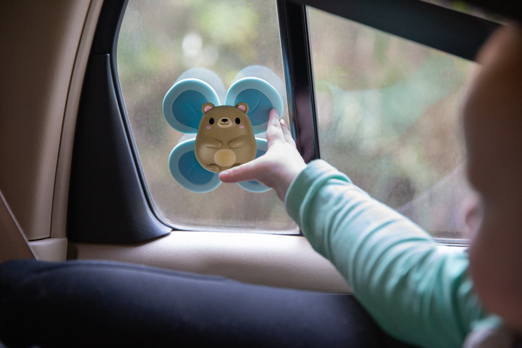 Bear Sensory Spinner affixed to a car window, showcasing its portability and secure suction for on-the-go sensory play.
