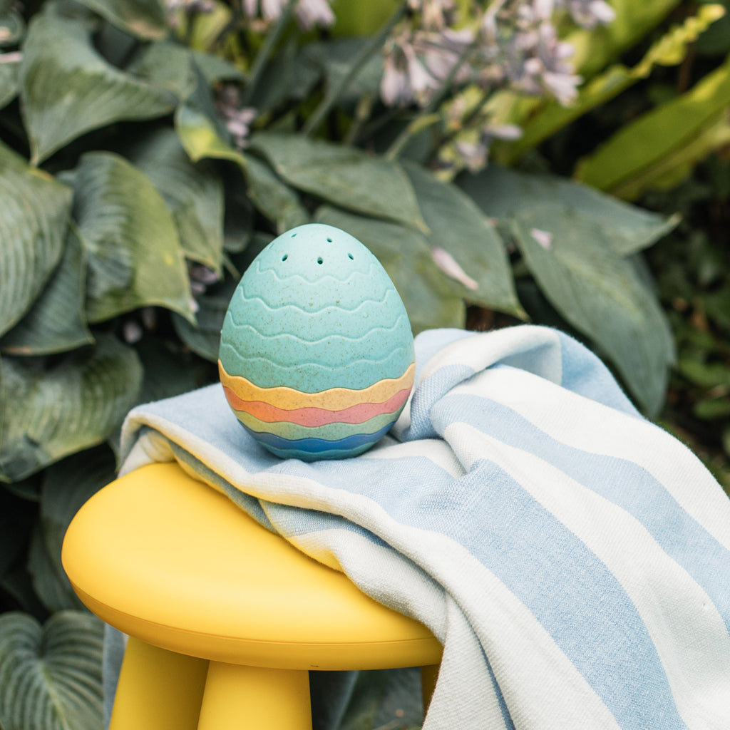 Bath Egg placed on towel and stool outdoors, showing off the natural aesthetic of the eco-friendly toy in a playful setup.