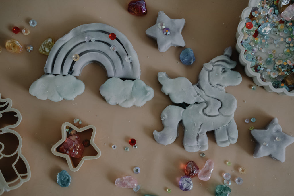 Children using biodegradable unicorn and rainbow cutters during sensory play with natural dough.