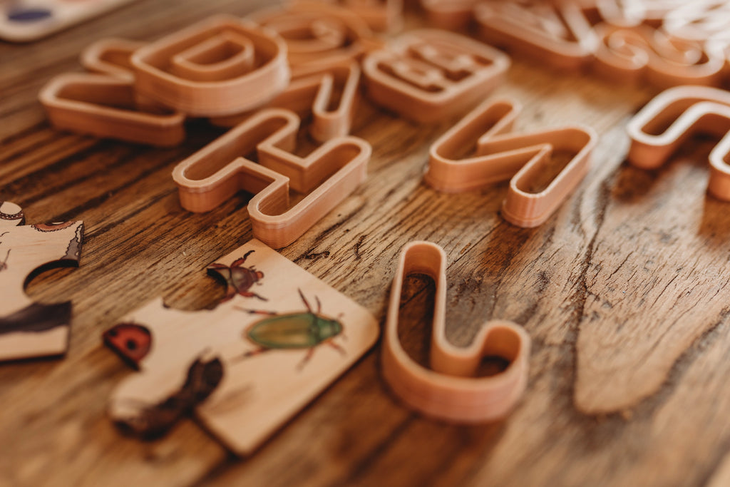 Eco Plastic letter-shaped playdough cutters on a wooden surface
