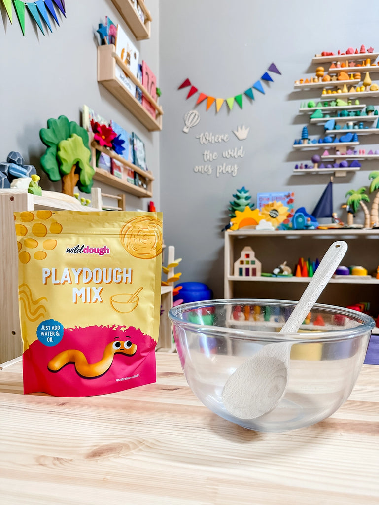 Wild Dough DIY Playdough Mix (Ywllow) pictured with mixing bowl and wooden spoonn in a playroom.