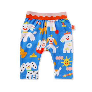 Flat lay of Halcyon Nights Puppy Park Baby Leggings featuring bright blue fabric with playful multicoloured dog, sun, and toy illustrations, plus a pink and red elastic waistband.