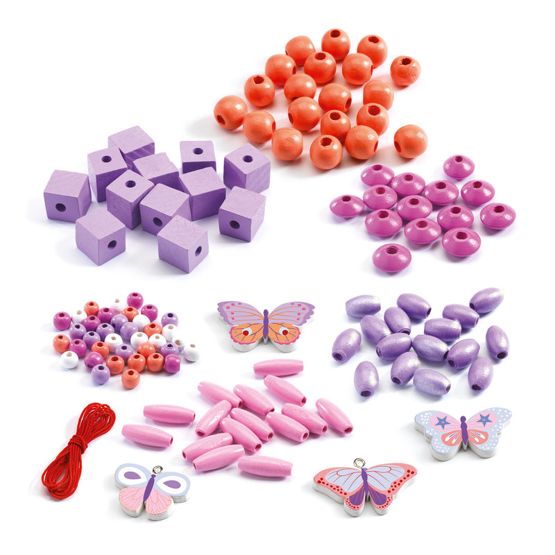 Flat lay of wooden bead kit contents including butterfly charms, beads in assorted shapes, and threading cord in pinks and purples