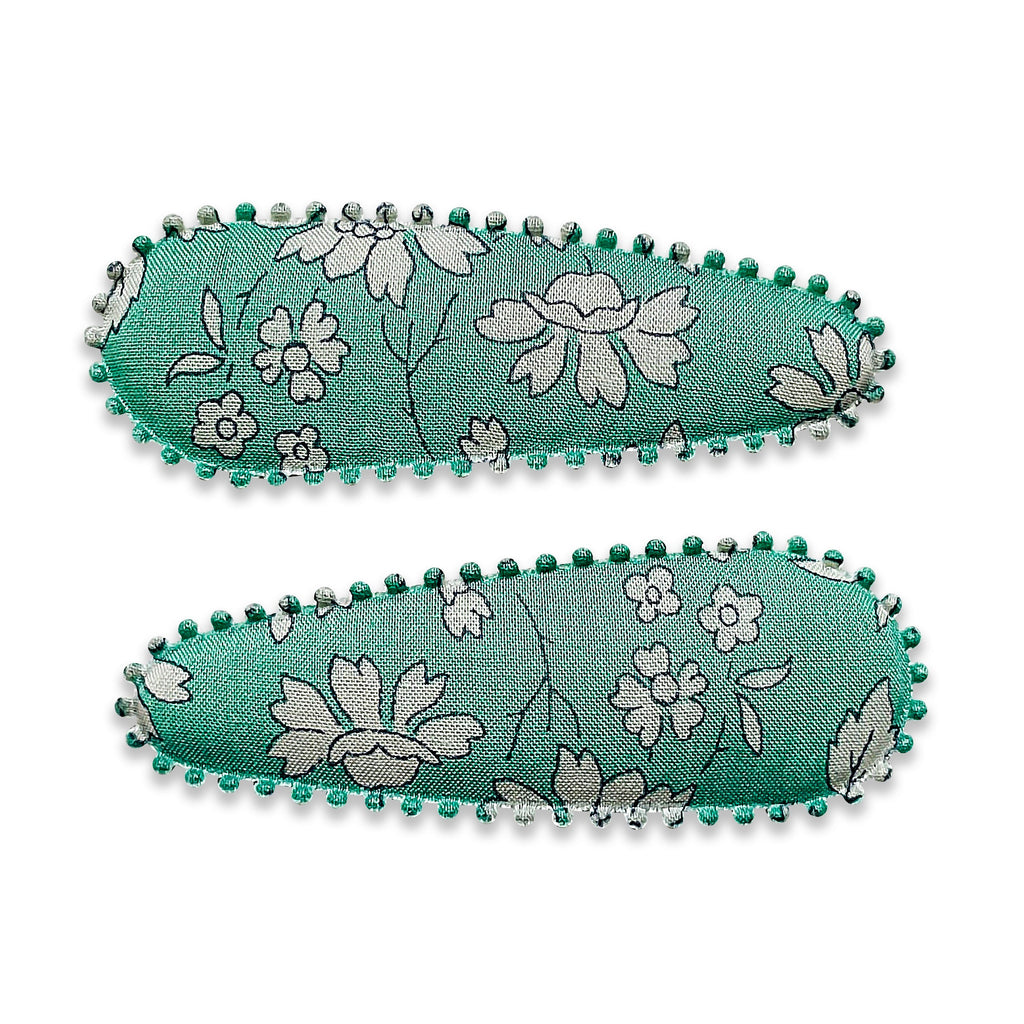 Two fabric-covered snap hair clips with a floral pattern and green scalloped edges.