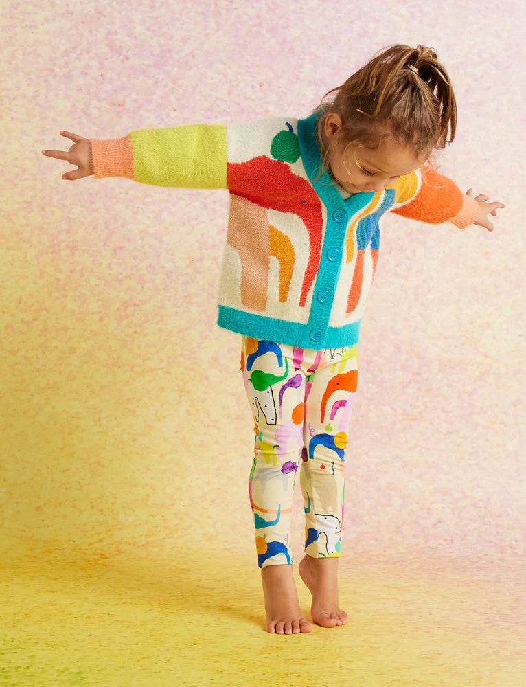 Child in Happy Herd Kids Leggings and a colourful jumper balancing barefoot on yellow floor with a joyful expression.