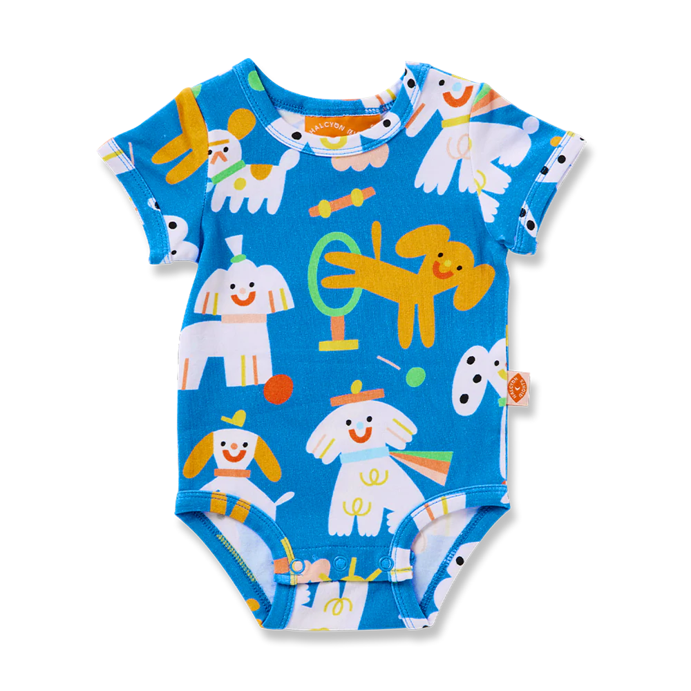Flat lay of Halcyon Nights Puppy Park Short Sleeve Bodysuit featuring a bright blue base with colourful puppy, sunshine, and toy illustrations.